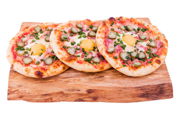 Three pizzas with ham, egg, pickled cucumber on a wooden tray. The object is isolated on a white background.