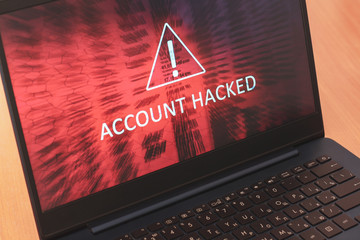 Laptop screen concept with white text Account hacked on red abstract background. Warning triangular...