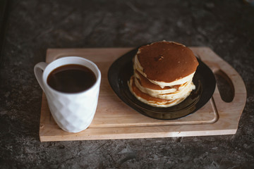a white mug and a stack of pancakes on a plate
