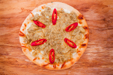 Pizza with curry sauce, meat, red pepper on a wooden background
