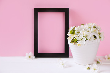 Empty frame with white cherry flowers on pink background,  white wooden board.  Creative layout , spring minimal concept. Spring mock up with empty space