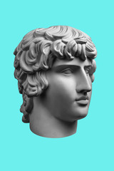 Gypsum copy of ancient famous statue Antinous head isolated on a light green background. Plaster antique sculpture young man face. Renaissance epoch.
