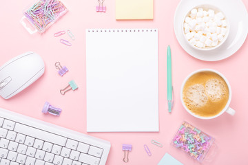 Woman office workplace with cup of coffee, notepad and stationery accessories on pink background. Top view