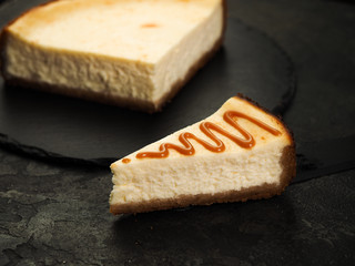 tasty homemade classic cheesecake new york and a slice of watered caramel topping on a dark background