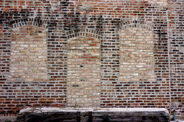 Old Brick Wall with bricked up windows and wooden bench