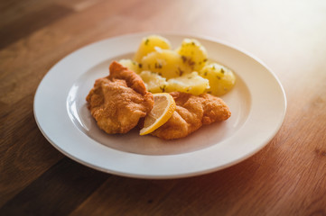 Steak with boiled potatoes on a white plate.