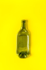 Green empty wine bottle on yellow desk from above