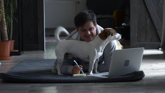Guy with a dog is working at home during the quarantine