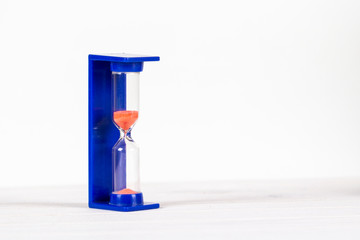 Blue glass hourglass on light background with copy space
