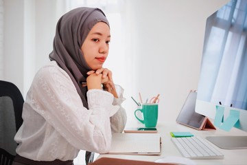 Asian muslim woman student or businesswoman waring hijab.Working from home with computer on table.Concept of social distancing working alone at home in the epidemic situation of covid-19.