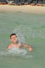 A happy caucasian child is swimming in the sea on summer vacation. A boy in a splash of water on a sunny day lifestyle