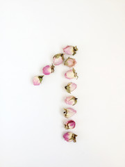 The number 1 is laid out of delicate pink small roses on a white background