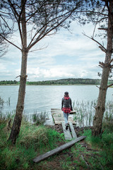 woman in leather coat walking by lake beach with wooden pier