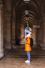 Fototapeta na wymiar woman tourist walking with backpack in yellow raincoat city tourism