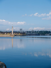 Obraz premium river pier. blue water. summer day at the river pier. clouds in the sky are reflected in the river.