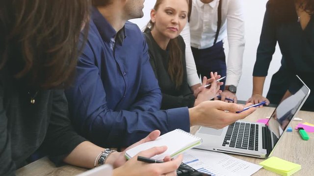 teamwork, group of business people talking in front of laptop computer in office or coworking space