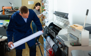 Worker loads new roll of paper into the plotter