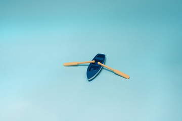 Small boat with oars on blue background