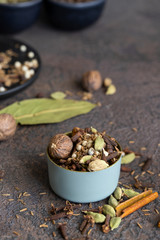 Different spices black and white peppercorns, cloves, cinnamon, mace, cardamom, cumin. Spice blend of ground spices in metal bowl on lthe table