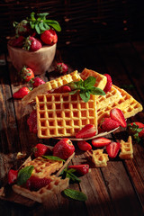 Naklejka na ściany i meble Waffles with strawberries and mint on a wooden table.