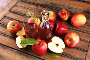 Apple cider drink and organic apples with leaves on table