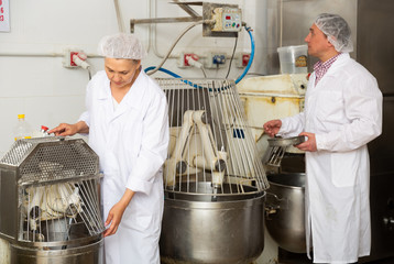 Woman and man controlling kneading of dough in bakery