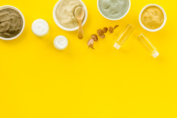 Set of cosmetic clays for facial beauty face mask on yellow table top-down frame space for text
