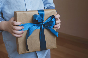 Little child holding gift on light background. Fathers day, birthday and holiday concept. Close up