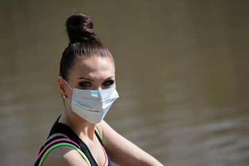 Beautiful portrait of a sports woman in a medical mask on a background of nature