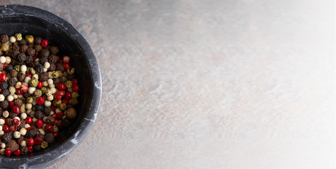 Top view of marble bowl with mix of different pepper, black ,white, pink ,green and allspice peppercorns .Large spice background for banner with copy space.
