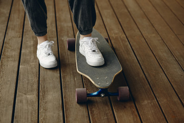 Teenager in white sneakers skateboarding on a wooden floor