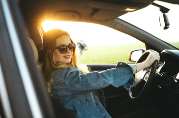 Naklejka premium Young beautiful blonde girl are smiling and having fun while driving the car. Adventure, travel, trip, tourism, driving car concept.