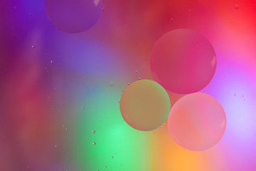 Top view movement of oil bubbles in the liquid. Oil surface multicolored background. Fantastic structure of colorful bubbles. Colorful artistic image of oil drop floating on the water