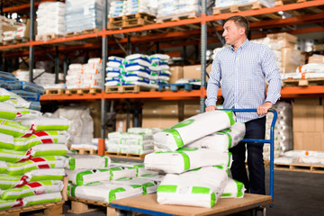Man choosing compost soil in plastic bags in hypermarket