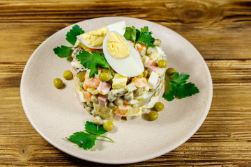 Traditional Russian festive salad Olivier on wooden table