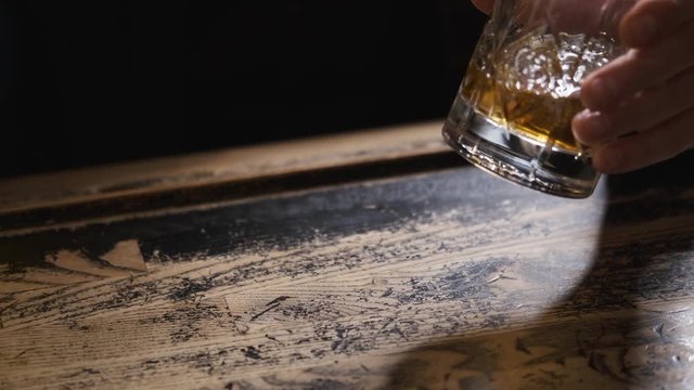 hands with glass on bar,glass rolling on table,man at bar,bokeh,bartender puts ice and takes glass of Bourbon, whiskey.order at bar,splashes of alcohol,concept alcohol, bar.Close-up, 4k
