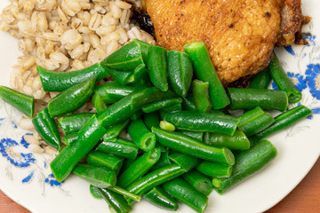 green asparagus beans on a plate with golden chicken thighs and pearl barley. healthy diet food.