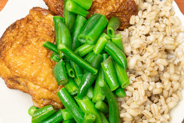 Tasty healthy dish of pearl barley porridge, oven-baked chicken thighs, green asparagus French beans.