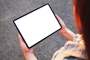 Top view mockup image of a woman holding black tablet pc with blank white screen in the outdoors street background © Farknot Architect