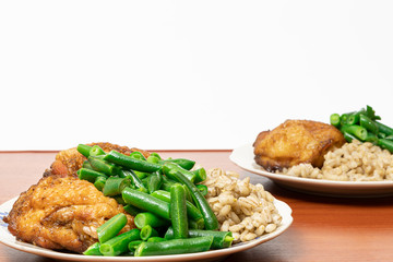 A delicious healthy dish of pearl barley porridge, oven-baked chicken thighs, green asparagus and French beans in a plate on the table.