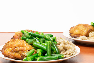 green asparagus beans on a plate with golden chicken thighs and pearl barley porridge on a table on a white background. healthy diet food.