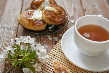 Pile of small homemade pancakes with honey, tea cup and honeycomb on wooden table