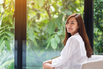 Portrait image of a beautiful asian woman with green nature outside the window