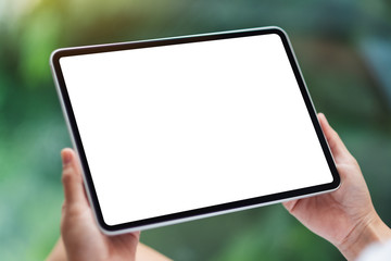 Fototapeta na wymiar Mockup image of a woman holding black tablet pc with blank white desktop screen , green nature background