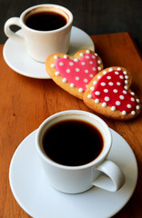 Two cups of coffee and dotted heart shaped royal icing cookies with selective focus