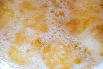 Top view Macro Close up motion of background surface detail view of hot golden shining yellow olive oil boiling deep frying and creating bubbles texture prepare cooking food in the kitchen restaurant