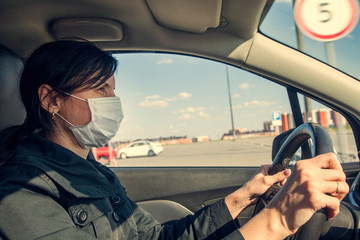 Young woman, beauty in a medical mask driving a car in town, New life in a pandemic