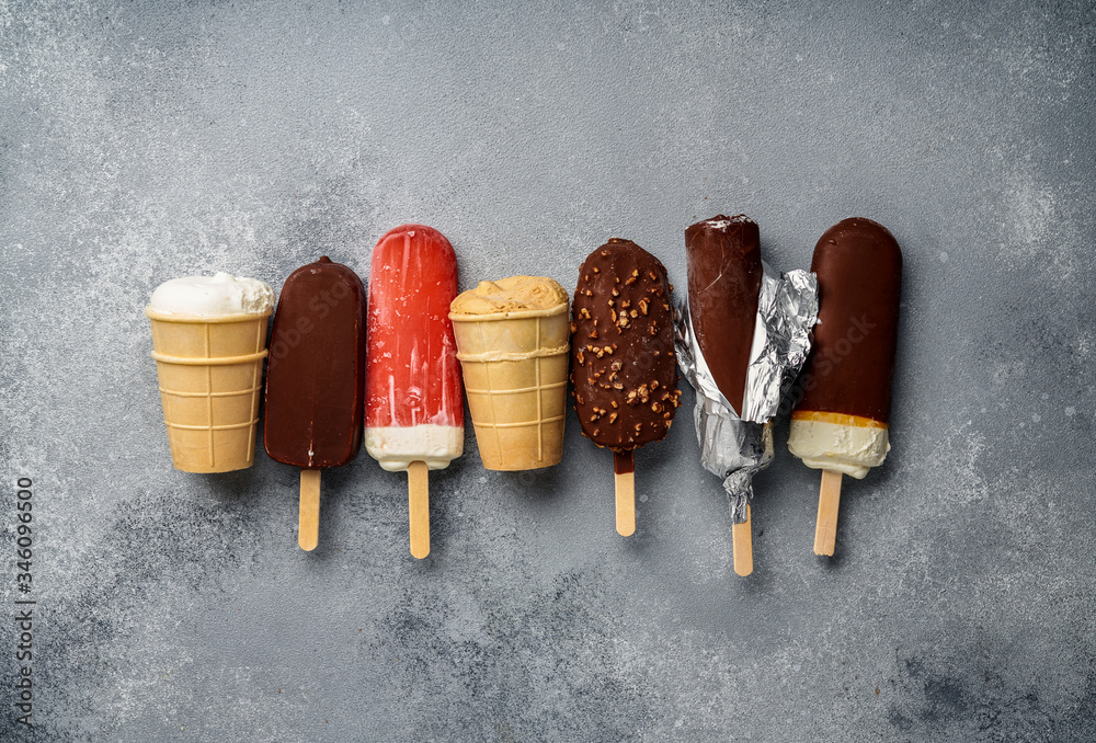 Wall mural Chocolate ice cream popsicles and fruit ice cream with cones on gray cold stone background. Copy space for text.