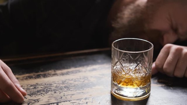 drunk man fell asleep at bar with glass of whiskey, Bourbon, Rum, feeling headache, Caucasian with beard and mustache, looks bad and upset, mumbles, close up, 4k