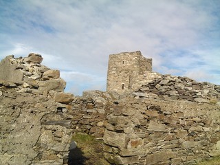 ruins of an old castle houses stones against the blue sky near the sea in Ireland